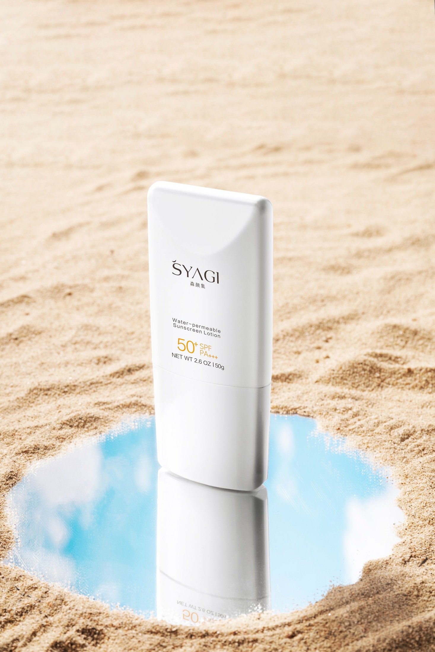 White sunscreen tube with a visible SPF 50 label standing on a small mirror set in pale sand; no foundation is mixed with it.