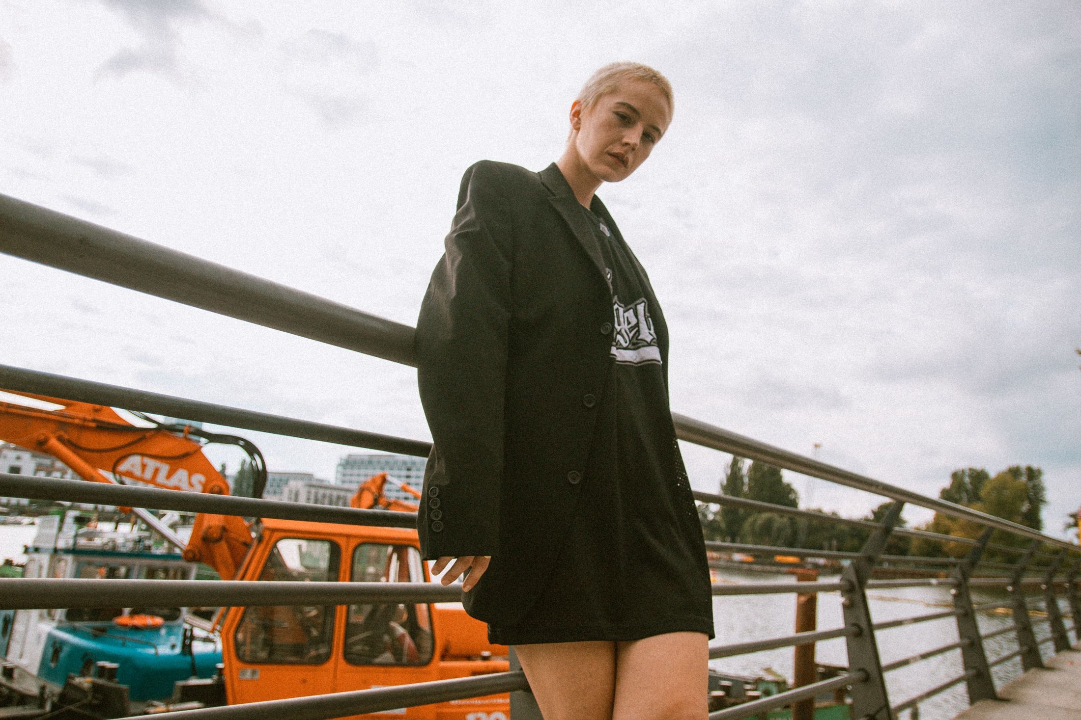Woman outdoors wearing a dark oversized blazer over a dark graphic crewneck T-shirt; the higher neckline sits inside the open lapels.
